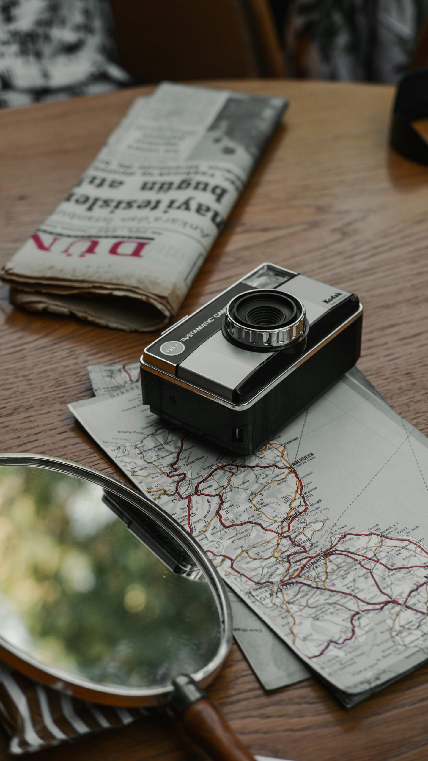 A camera sitting on top of a wooden table next to a magnifying glass